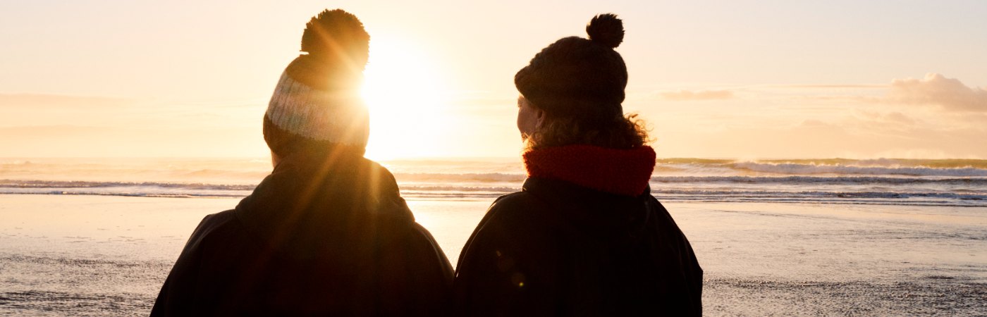 2 women walking on the beach on a sunny, winters day