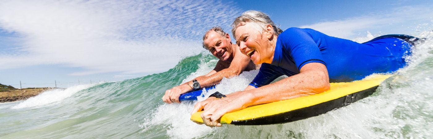 Senior couple bodyboarding in the sea